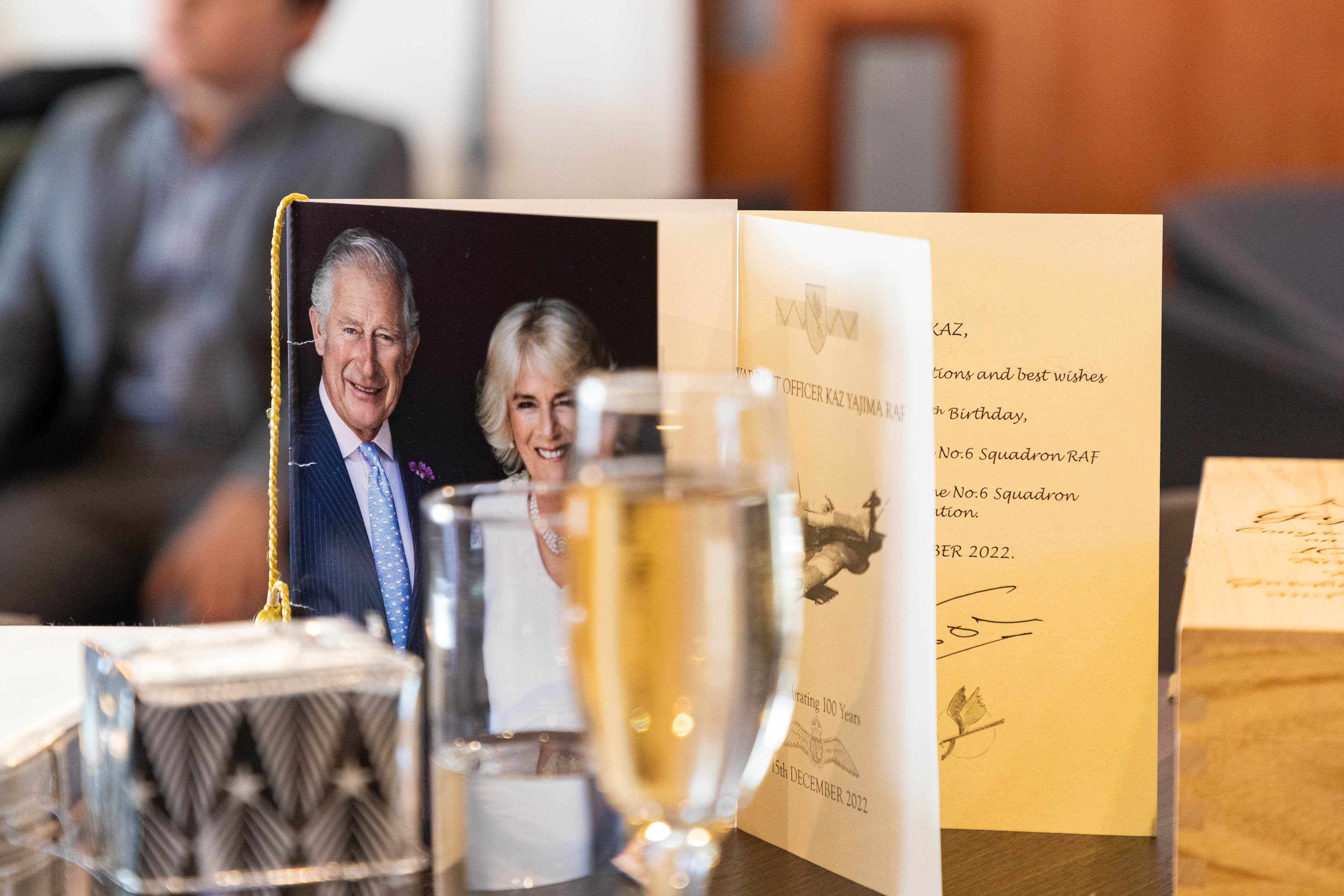 Image shows table with birthday card, a picture of His Majesty the King George the third and the Queen in consort Camilla.
